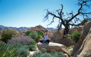 woman meditating on a rock in the desert
